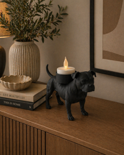 Matte zwarte Staffordshire Bull Terrier waxinelichthouder met LED-waxinelichtje op kastje in sfeervolle woonkamer.